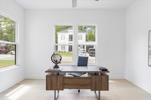 office area with light wood-type flooring, ceiling fan, and baseboards