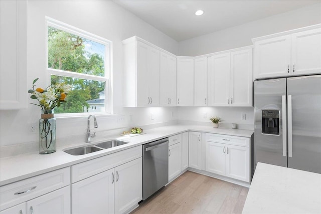 kitchen featuring stainless steel appliances, a sink, light countertops, healthy amount of natural light, and recessed lighting