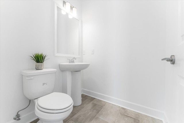 bathroom with toilet, baseboards, and a sink