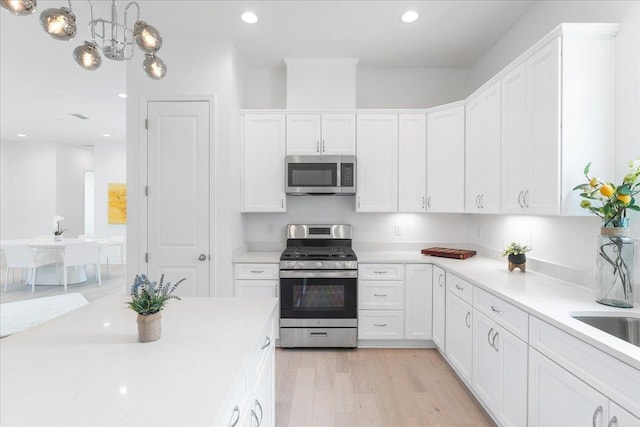 kitchen featuring stainless steel appliances, white cabinets, light countertops, recessed lighting, and light wood-style flooring