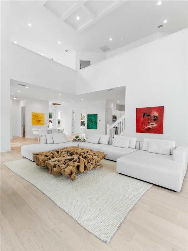 living area with wood finished floors, a high ceiling, recessed lighting, and baseboards