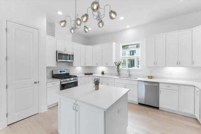 kitchen featuring appliances with stainless steel finishes, a sink, white cabinets, light wood finished floors, and recessed lighting