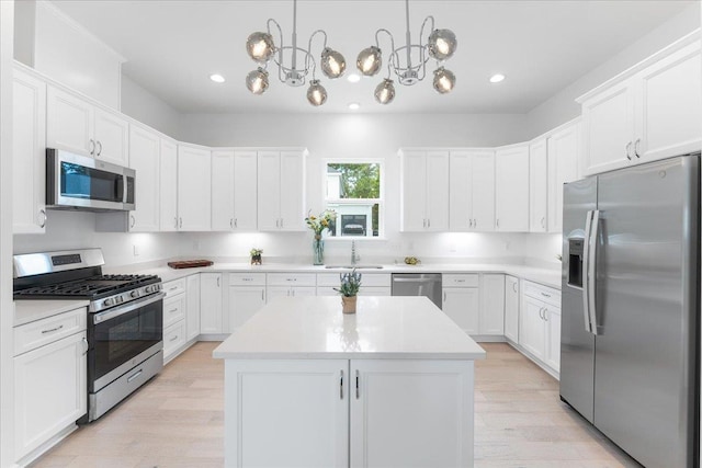 kitchen featuring stainless steel appliances, a sink, a chandelier, a center island, and light countertops