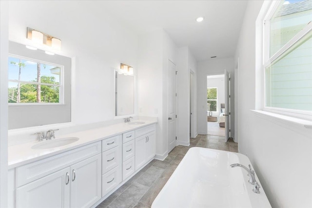 bathroom with a soaking tub, healthy amount of natural light, and double vanity