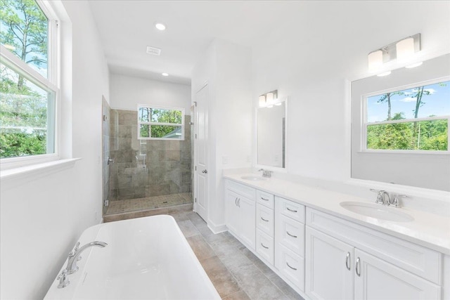 bathroom featuring tiled shower, double vanity, recessed lighting, and a freestanding bath