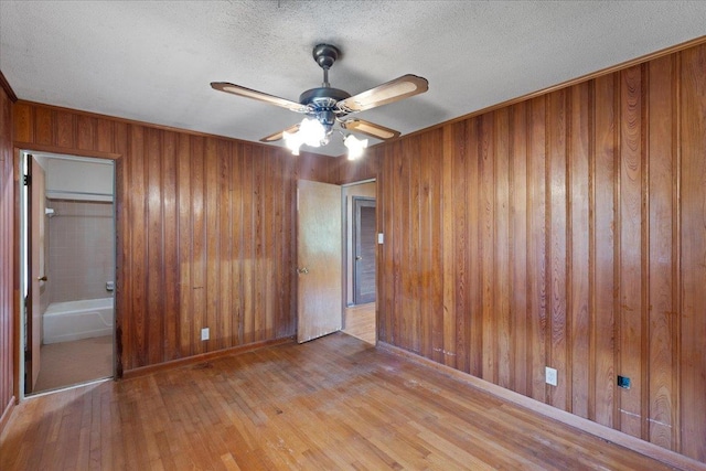 203 Forest Cir, Perry, FL 32347 - unfurnished bedroom featuring wood-type flooring, wooden walls, a textured ceiling, and a ceiling fan
