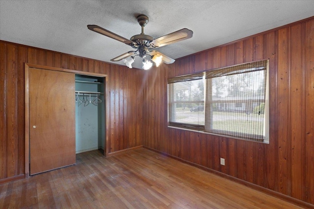 203 Forest Cir, Perry, FL 32347 - unfurnished bedroom with wood walls, wood finished floors, a closet, a textured ceiling, and ceiling fan