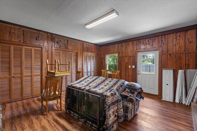 203 Forest Cir, Perry, FL 32347 - bedroom with wooden walls, wood finished floors, a textured ceiling, and multiple closets