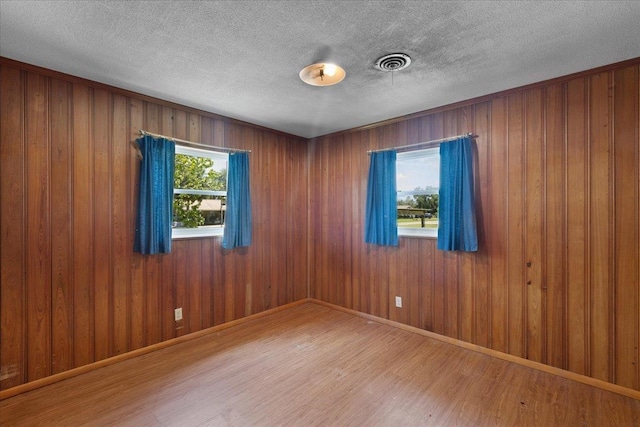 203 Forest Cir, Perry, FL 32347 - unfurnished room with wood finished floors, wooden walls, and a textured ceiling