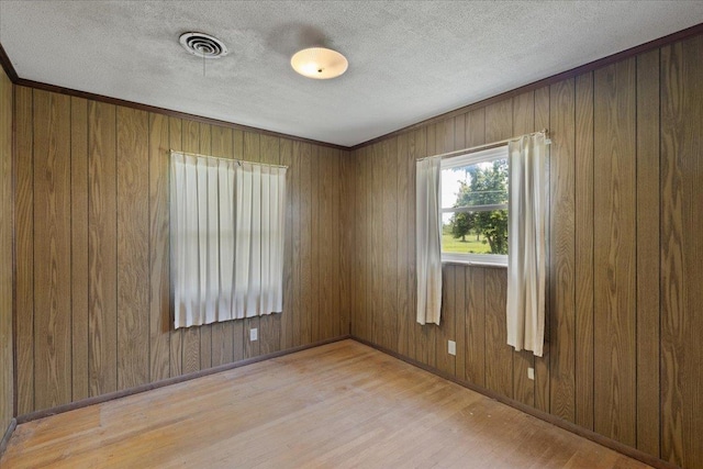 203 Forest Cir, Perry, FL 32347 - spare room featuring wood finished floors, wood walls, and a textured ceiling