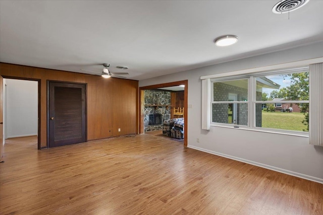 203 Forest Cir, Perry, FL 32347 - unfurnished living room with a fireplace, light wood-type flooring, wood walls, and ceiling fan