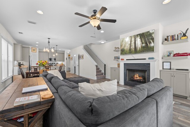 2848 Crestline Rd, Tallahassee, FL 32308 - living room with a warm lit fireplace, recessed lighting, ceiling fan, light wood-type flooring, and a chandelier