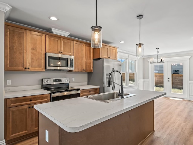 kitchen with stainless steel appliances, light hardwood / wood-style floors, hanging light fixtures, and sink