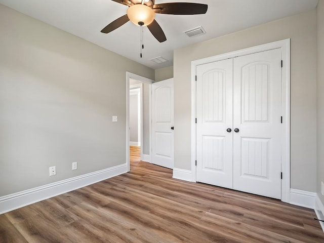 unfurnished bedroom with hardwood / wood-style floors, ceiling fan, and a closet