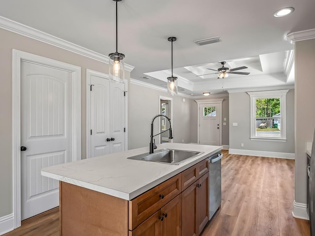 kitchen with sink, a kitchen island with sink, ornamental molding, pendant lighting, and light wood-type flooring