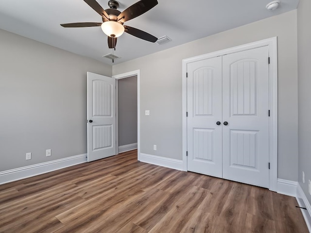 unfurnished bedroom featuring a closet, wood-type flooring, and ceiling fan