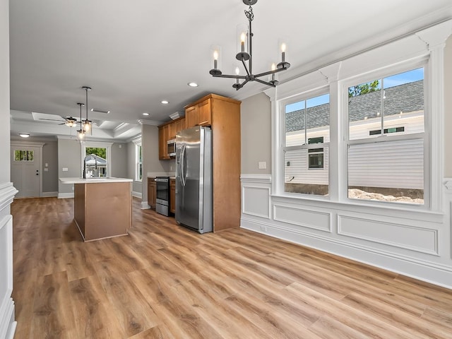 kitchen featuring pendant lighting, ceiling fan with notable chandelier, light hardwood / wood-style flooring, and appliances with stainless steel finishes