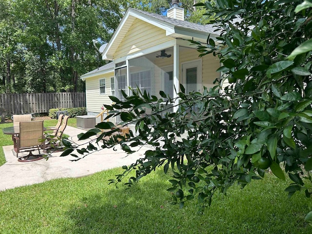 view of side of property featuring a lawn, a sunroom, and a patio area