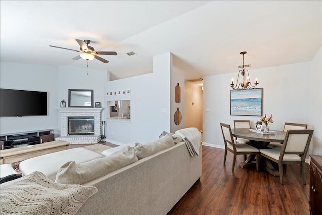 living room featuring a fireplace, dark hardwood / wood-style floors, and ceiling fan with notable chandelier