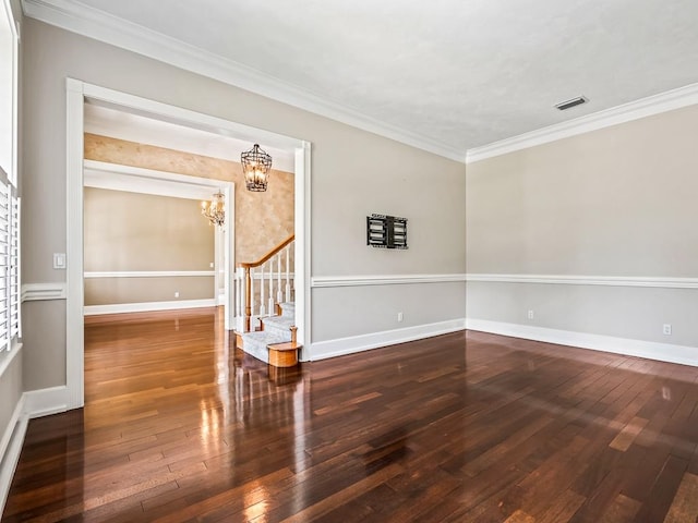 unfurnished room with ornamental molding, a notable chandelier, and dark wood-type flooring