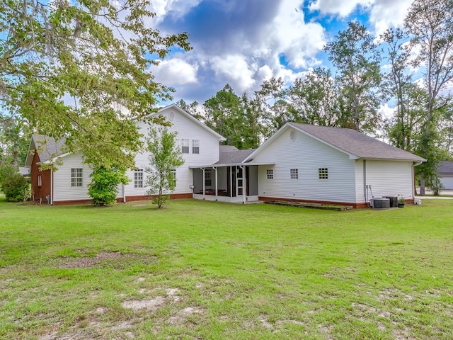 rear view of house featuring central air condition unit, a sunroom, and a yard