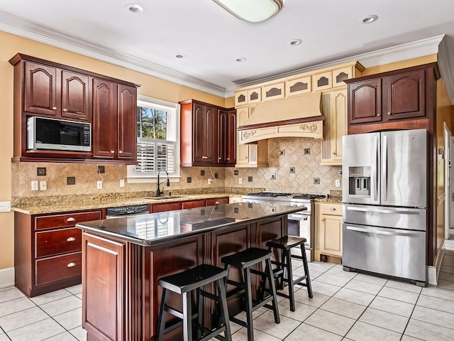 kitchen with appliances with stainless steel finishes, ornamental molding, a kitchen breakfast bar, custom exhaust hood, and a kitchen island