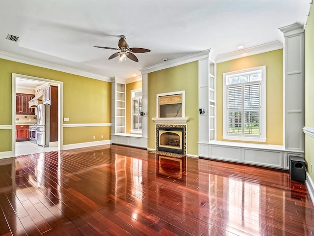 unfurnished living room with wood-type flooring, ornamental molding, ceiling fan, a fireplace, and built in features