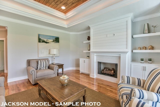 living room featuring a large fireplace, built in features, light hardwood / wood-style flooring, and crown molding