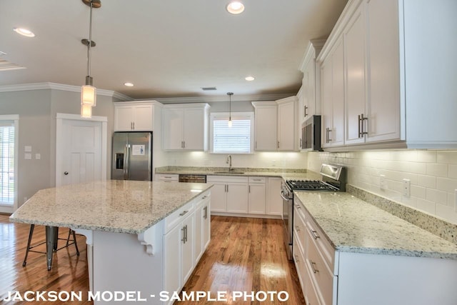 kitchen featuring appliances with stainless steel finishes, hanging light fixtures, and a healthy amount of sunlight