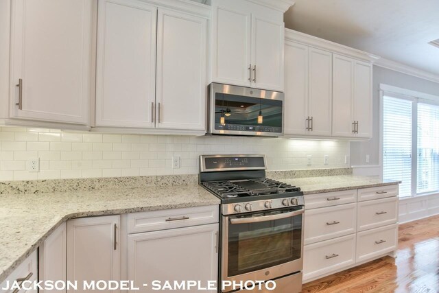 kitchen featuring stainless steel appliances, light stone counters, backsplash, light hardwood / wood-style flooring, and white cabinets