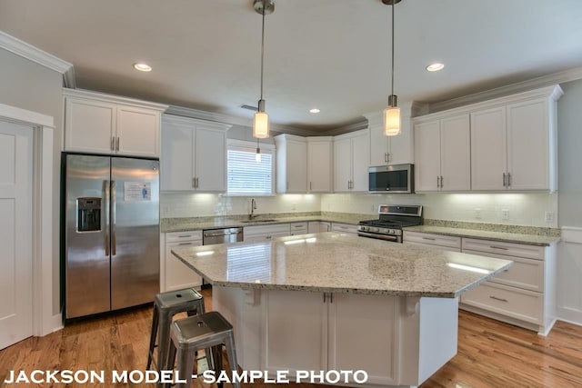 kitchen featuring white cabinetry, stainless steel appliances, and hanging light fixtures