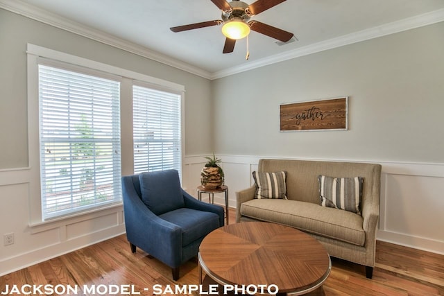 sitting room with hardwood / wood-style flooring, ceiling fan, and crown molding