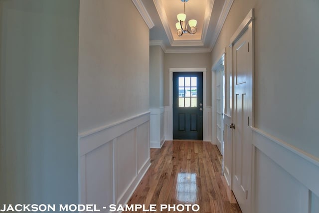 entryway with light hardwood / wood-style floors, a notable chandelier, crown molding, and a tray ceiling