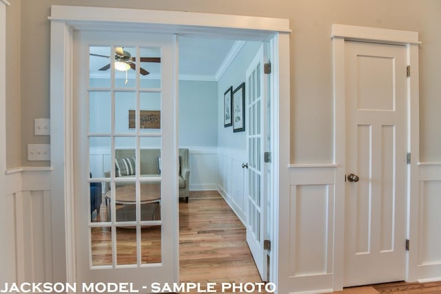 doorway with light hardwood / wood-style floors, ceiling fan, and crown molding