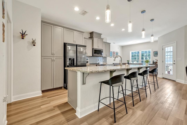 323 Carr Ln, Tallahassee, FL 32312 - kitchen with stainless steel appliances, gray cabinets, a kitchen bar, light wood-type flooring, and recessed lighting