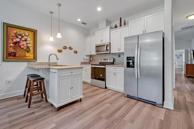 323 Carr Ln, Tallahassee, FL 32312 - kitchen with appliances with stainless steel finishes, a sink, tasteful backsplash, white cabinetry, and light wood-type flooring