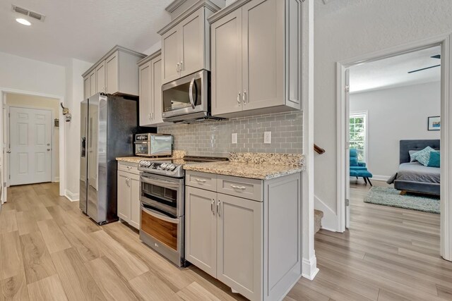 323 Carr Ln, Tallahassee, FL 32312 - kitchen with stainless steel appliances, gray cabinets, tasteful backsplash, and light wood finished floors