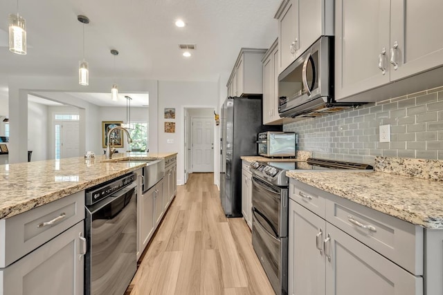 323 Carr Ln, Tallahassee, FL 32312 - kitchen with appliances with stainless steel finishes, light wood-style floors, gray cabinetry, a sink, and tasteful backsplash