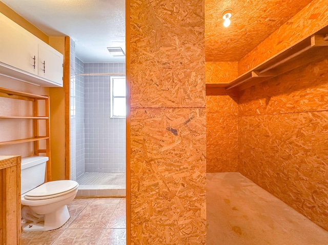 bathroom with tiled shower, a textured ceiling, and toilet