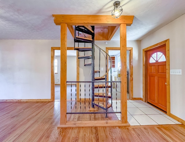 foyer entrance with a textured ceiling and light hardwood / wood-style flooring