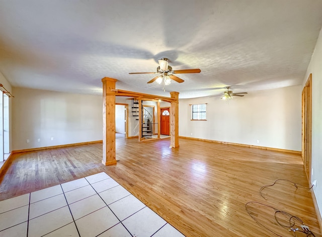 unfurnished living room with a textured ceiling, light hardwood / wood-style flooring, and ceiling fan