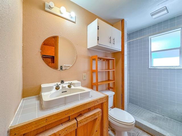 bathroom with a tile shower, vanity, and toilet