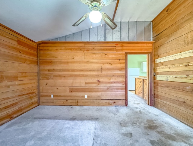 carpeted spare room featuring wooden walls and lofted ceiling