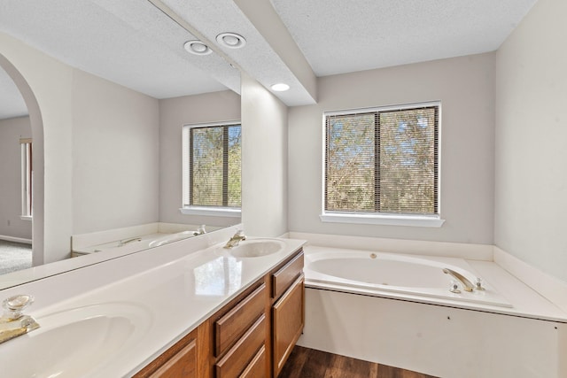 bathroom with a washtub, vanity, hardwood / wood-style floors, and a textured ceiling