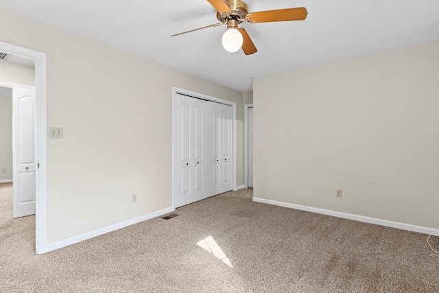 unfurnished bedroom featuring ceiling fan, a closet, and light carpet