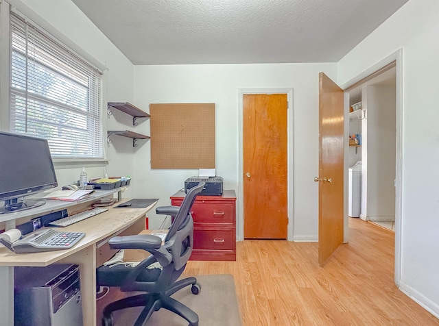 office featuring a textured ceiling, light hardwood / wood-style floors, and washer / clothes dryer