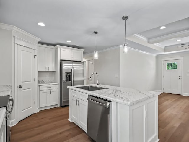 kitchen featuring appliances with stainless steel finishes, white cabinetry, an island with sink, sink, and hanging light fixtures