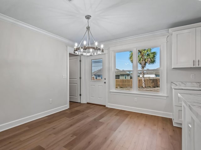 unfurnished dining area with hardwood / wood-style floors, crown molding, and a notable chandelier