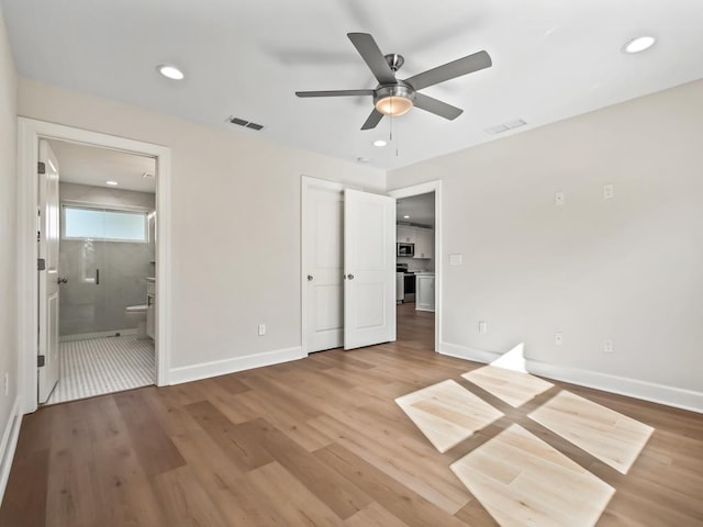 unfurnished bedroom with ensuite bathroom, hardwood / wood-style floors, ceiling fan, and a closet