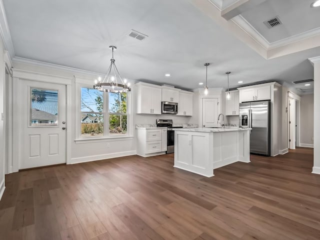 kitchen with white cabinetry, stainless steel appliances, hanging light fixtures, and a center island with sink